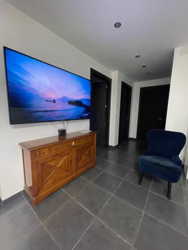 un salon avec une grande télévision et une chaise bleue dans l'établissement Appartement 6 couchages, à Sainte-Maxime