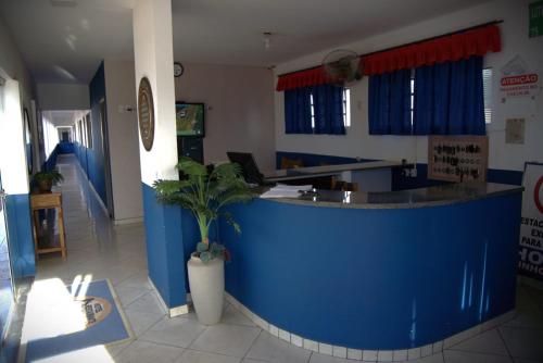 a lobby with a blue counter with a potted plant at Hotel Sinhozinho in Coxim