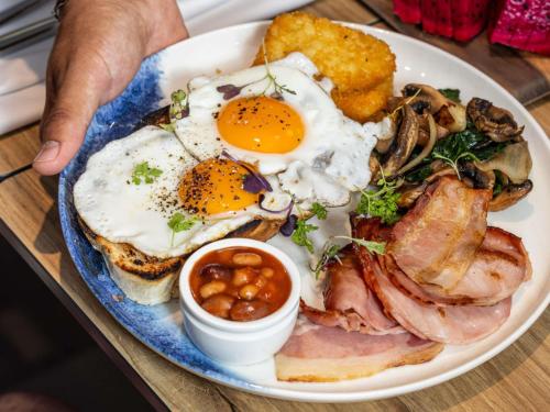 a plate of breakfast food with eggs and bacon at Mercure Darwin Airport Resort in Darwin