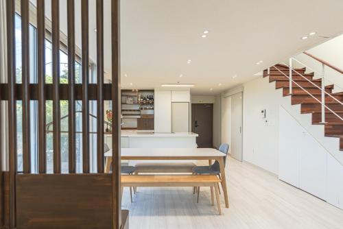 ein Esszimmer mit einem Tisch und einer Treppe in der Unterkunft Aewol Damdam Stay in Sowang-dong