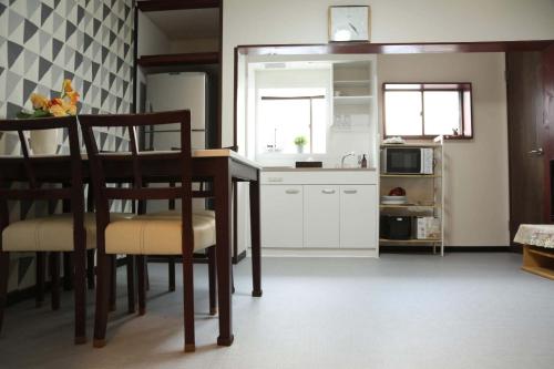 een keuken met een tafel, stoelen en een magnetron bij サンハウス 2 in Osaka