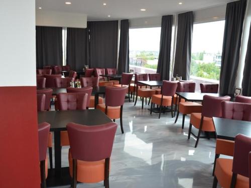 a dining room with tables and chairs and windows at C & N Hostel München in Munich