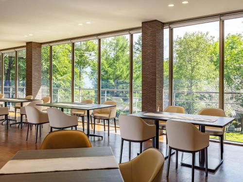 a dining room with tables and chairs and windows at Wan Wan Paradise Yatsugatake in Hokuto