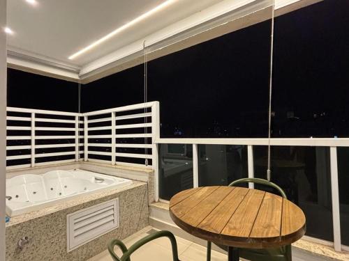 ein Badezimmer mit Badewanne, einem Holztisch, einem Tisch und einer Tischplatte in der Unterkunft Flat | Linda vista | Ao lado do Goiânia Shopping in Goiânia
