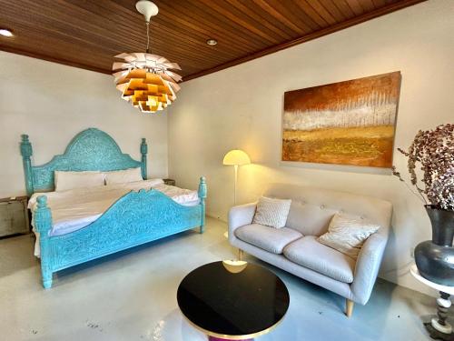 a bedroom with a blue bed and a couch at Chic Designer Family Suite in Shared Bungalow near LRT SS1 PJ in Petaling Jaya