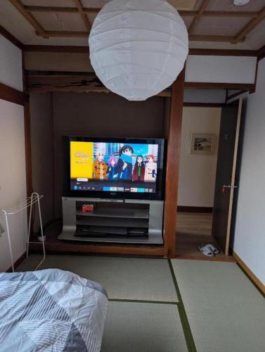 a living room with a flat screen tv and a lamp at ゲストハウスあじす201 in Yamaguchi