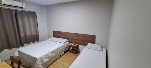 a small room with two beds and a radiator at Hotel Brivanna in Campo Grande