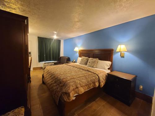 a bedroom with a bed and a blue wall at Garden Inn and Extended Stay in Shepherdsville