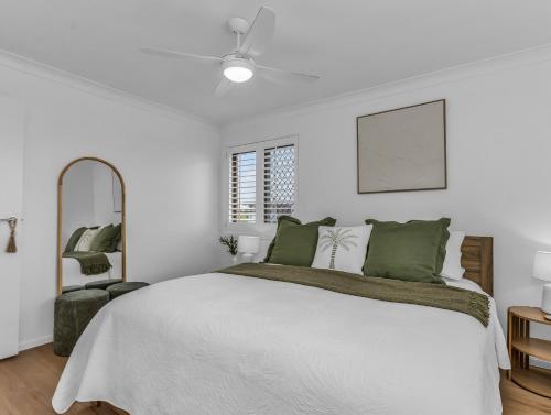 a white bedroom with a bed and a mirror at Wave Whisperer in Kingscliff