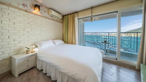 a bedroom with a white bed and a large window at tongyeong haegando pension in Tongyeong