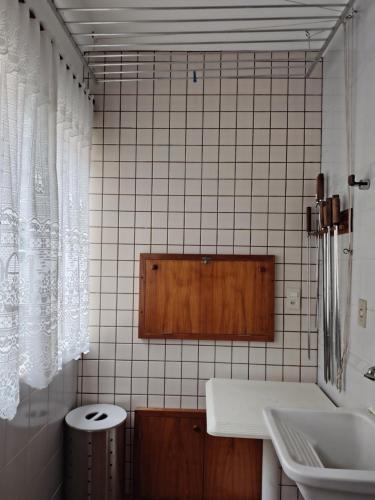 ein weiß gefliestes Bad mit einem Waschbecken und einem WC in der Unterkunft Aconchegante apto em Capao da Canoa in Capão da Canoa