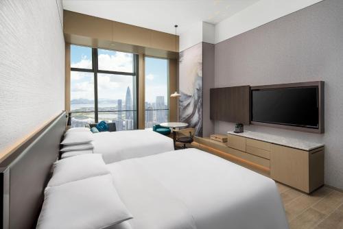 a hotel room with four beds and a flat screen tv at Renaissance Shenzhen Bay Hotel in Shenzhen