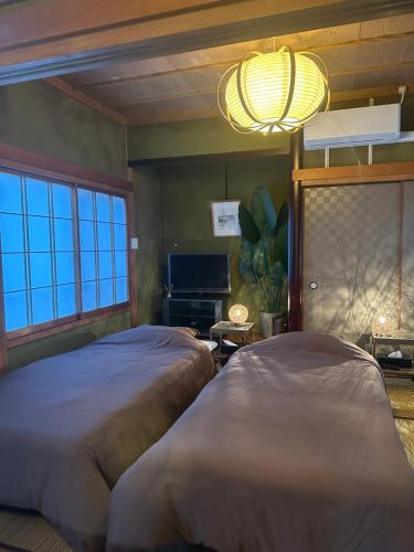 a bedroom with two beds and a large window at Guest House "Ro"Ikura in Shimonoseki