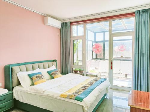 a bedroom with a bed and a large window at Jinshanling Gubeikou Great Wall聚友缘民宿 in Gubeikou