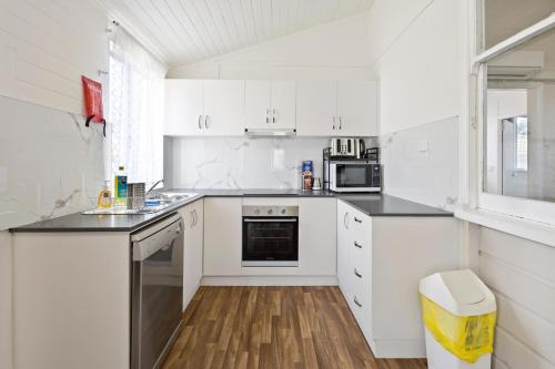 a white kitchen with white cabinets and a window at CBD Holiday Home in Mackay