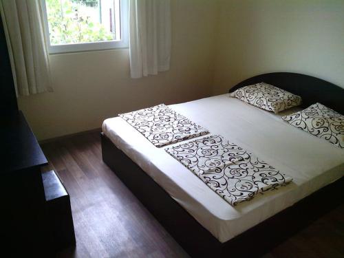 a bed in a bedroom with a white bedspread and pillows at Bungalows St. Nicola in Ahtopol