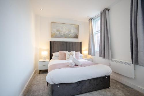 a bedroom with a bed with white sheets and a window at Stylish 1BR Apt near Cardiff Castle in Cardiff