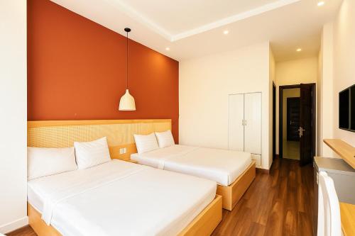 twee bedden in een kamer met oranje muren bij Saigon Central Hotel in Ho Chi Minh-stad