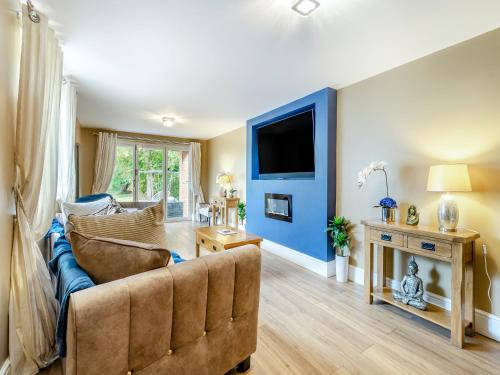 a living room with a couch and a tv at Lovetts Bridge Cottage in Atherstone