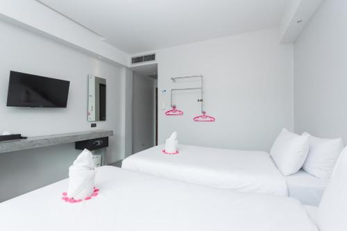 two white beds in a room with a tv at Riverside Hotel in Krabi town