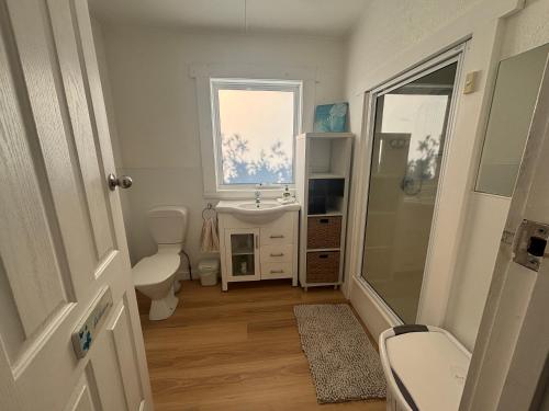 a bathroom with a sink and a toilet and a window at Port Sorell Beach Shack in Port Sorell