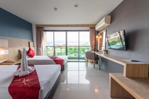 une chambre d'hôtel avec deux lits et une grande fenêtre dans l'établissement Arawana Regency South Pattaya, à Pattaya (sud)