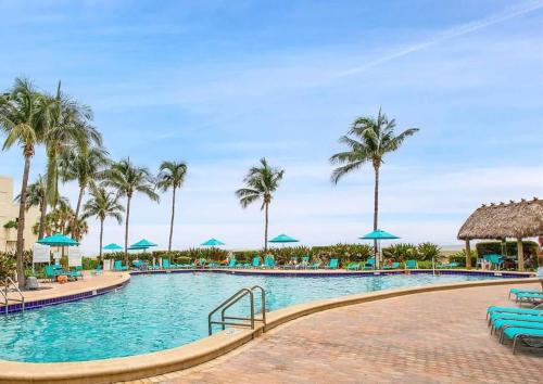 a swimming pool at a resort with palm trees at Oceanfront Penthouse with Intercoastal Views in Hollywood Beach