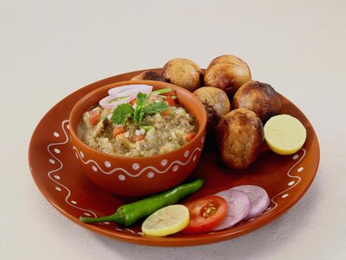 a bowl of food on a plate with potatoes and vegetables at Super Hotel O Gaya Railway Junction Formerly Family Guest House in Gaya