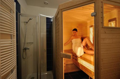 Uma mulher está sentada numa sauna. em Hotel Joseph 1699 em Trebic