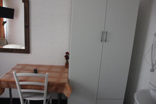 a dining room table with a white chair and a mirror at Airport-Hotel zum Taubengrund in Kelsterbach