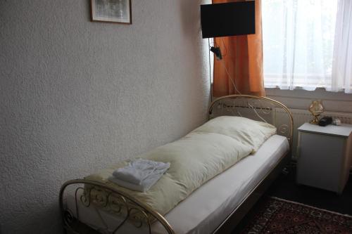 a small bed in a room with a window at Airport-Hotel zum Taubengrund in Kelsterbach