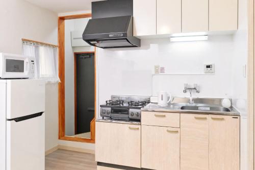 a kitchen with a stove and a sink and a microwave at Hagi in Tokyo