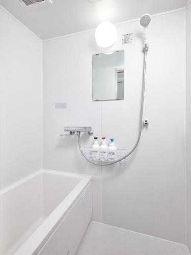 a white bathroom with a tub and a mirror at Hagi in Tokyo