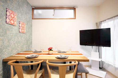 a dining room with a wooden table and a television at Hagi in Tokyo