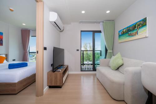 a bedroom with a bed and a couch and a tv at Space Cherngtalay Condo in Elegant Bang Tao in Ban Thalat Choeng Thale