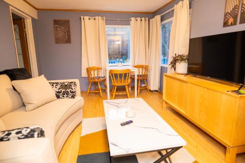 a living room with a couch and a tv and a table at 3 Bedroom Gardenside Downtown Home in Whitehorse