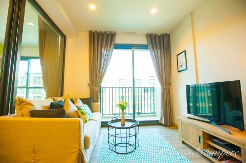 a living room with a yellow couch and a tv at Raincondo Ampere in Cha Am