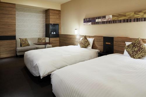 una habitación de hotel con dos camas y una silla en Mitsui Garden Hotel Sapporo, en Sapporo