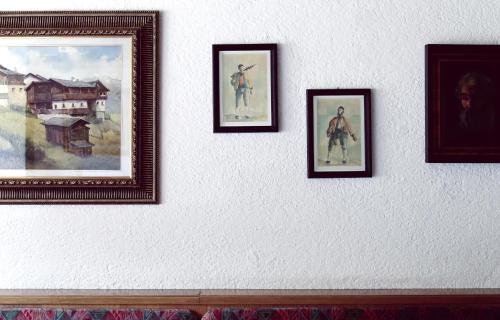 a wall with four framed paintings on it at Hotel & Suites Glück Auf in Mayrhofen