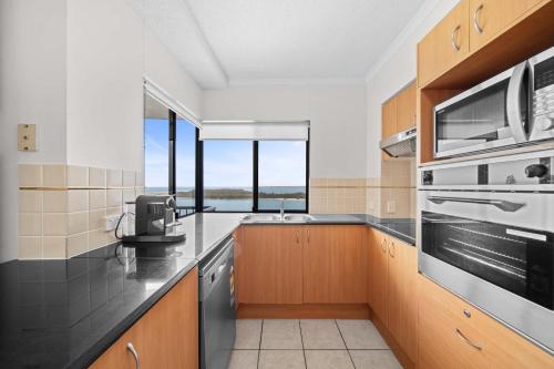 una cocina con fregadero y estufa horno superior en Seaside Solace at Caloundra Seaview 3BD Apartment, en Caloundra