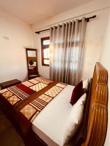a bedroom with a large bed with a window at The Budget White House Hotel in Nuwara Eliya