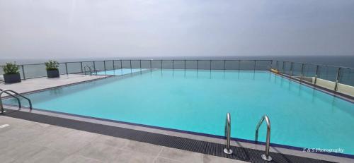 a large blue swimming pool with the ocean in the background at Chilax By The Ocean in Dehiwala