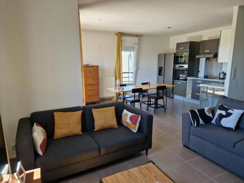 un salon avec un canapé et une cuisine dans l'établissement Magnifique appartement, à Prévessin-Moëns