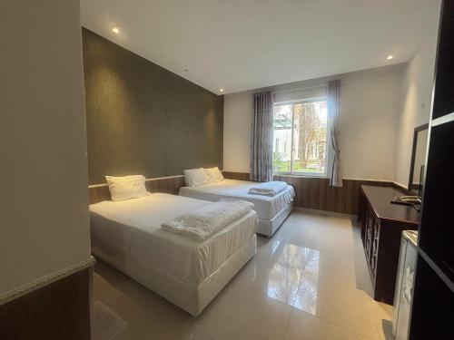 a hotel room with two beds and a window at Hoang Cung Hotel in Ấp Phú Thọ