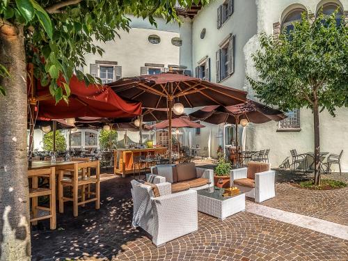 an outdoor patio with tables and chairs and umbrellas at Casa del Vino della Vallagarina in Isera