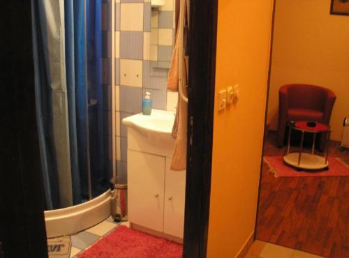 a bathroom with a sink and a toilet and a chair at Rooms Zeko in Aljmaš