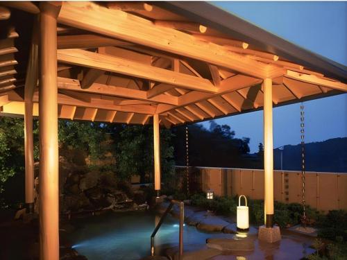 a wooden pergola with a pond in a yard at Yugawara Onsen Hotel Akane in Mongawa