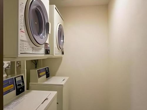 a laundry room with three washing machines on a wall at a.Suehiro Hotel in Oita