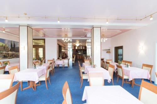 a dining room with white tables and chairs at Hotel Heldt in Bremen