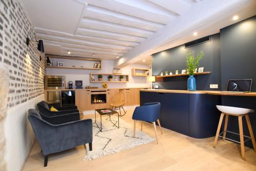 Il comprend un salon avec un comptoir et des chaises ainsi qu'une cuisine. dans l'établissement Victoire & Germain, à Paris